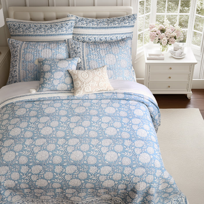 Bed with blue floral bedding in a bright bedroom