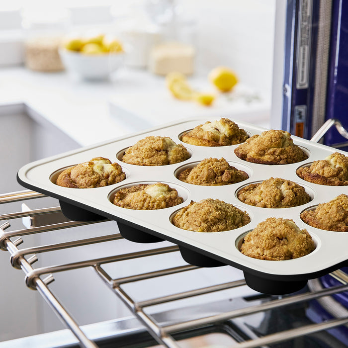 GreenLife green ceramic nonstick muffin pan with nine baked muffins on a kitchen counter.