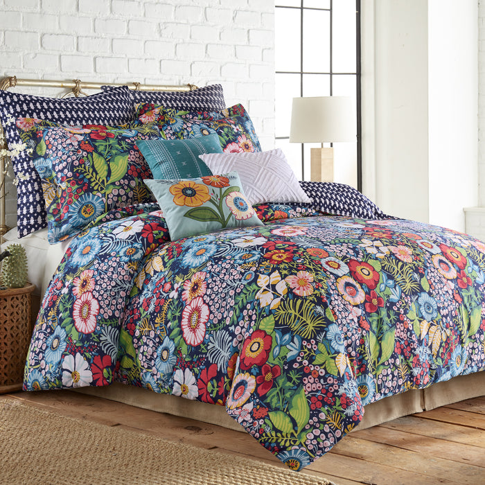 Colorful floral bedding set on a bed with pillows in a bedroom setting.