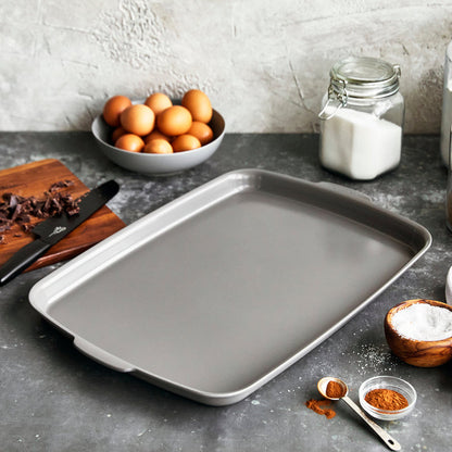 Gray ceramic nonstick half sheet pan on counter with eggs, sugar, and spices in the background.