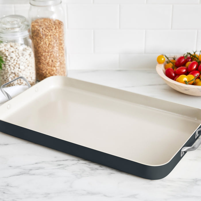 Black double griddle on a marble counter, with jars of beans and cherry tomatoes nearby.