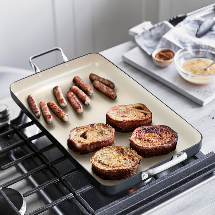 Sausages and French toast cooking on a black Rio Double Griddle with ingredients beside the griddle.