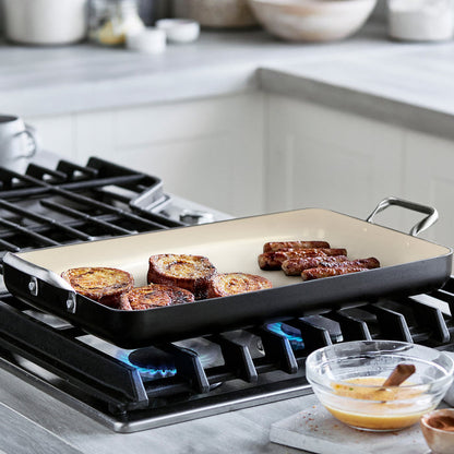 Black Rio double griddle on stovetop with sausage links; bowl of whisked eggs beside it.