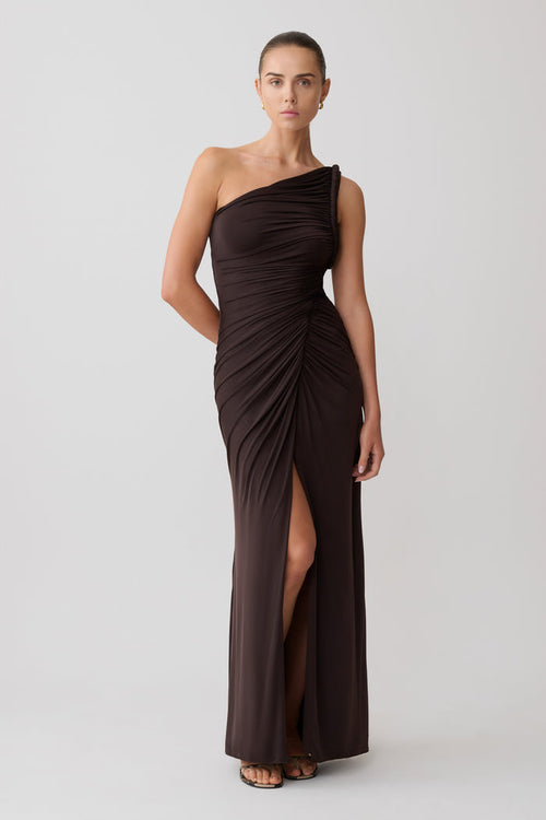 Woman wearing a brown one-shoulder maxi dress with a slit.