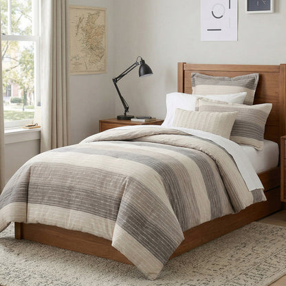 Bedroom with a bed featuring striped bedding, wooden headboard, and lamp.
