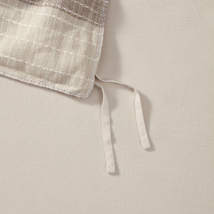 Close-up of a beige fabric with a textured edge on a light background