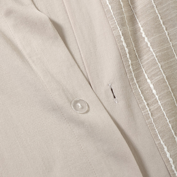 Close-up of a beige fabric with a button and white stripe detail