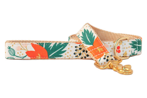 A cheerful floral dog leash with bold orange and leafy botanical prints with metallic accents on a light background, finished with luxe hardware for a standout walk-time look.