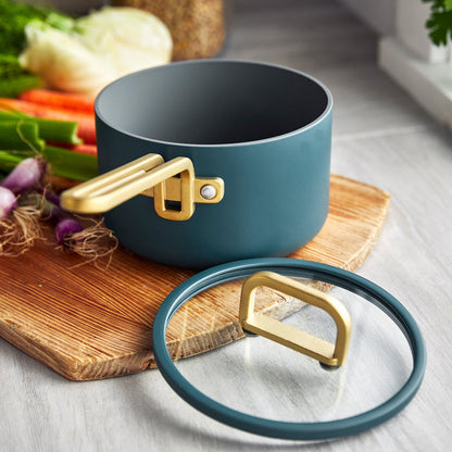 Venetian teal 2-quart saucepan with lid on a wooden board, surrounded by assorted fresh vegetables.