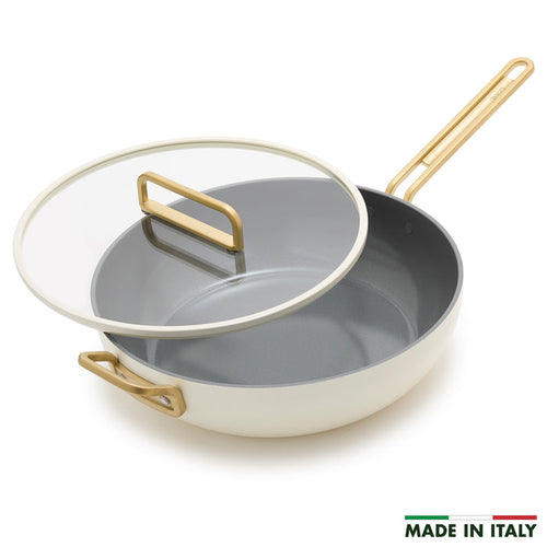 White ceramic 6.5-quart pan with gold handles and a glass lid.