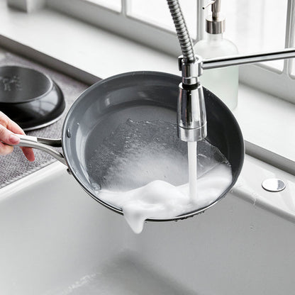 Hand washing a soapy 8-inch Swift ceramic nonstick frypan under running water in a kitchen sink.