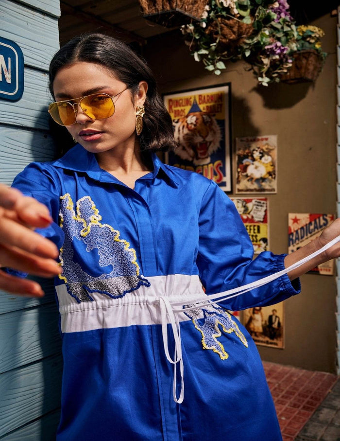 Wild Royal Blue Shirt Dress with abstract blue and yellow embroidery, contrasting white drawstring waist panel, and three-quarter sleeves in a chic relaxed silhouette.
